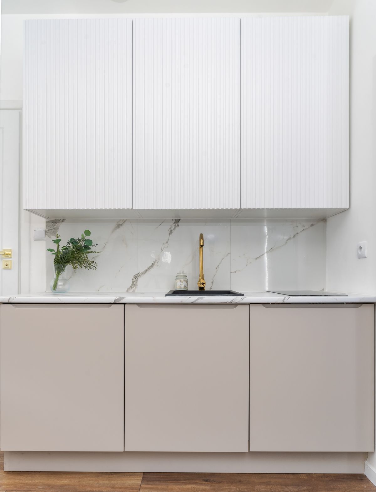 A modern kitchen with a marble backsplash and light cabinets